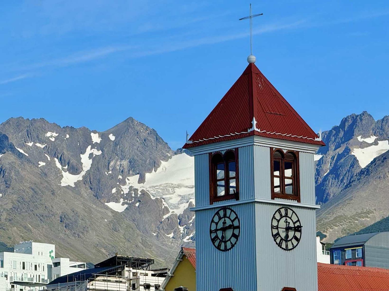 Paisagem urbana de Ushuaia com montanhas ao fundo e um lago à frente.