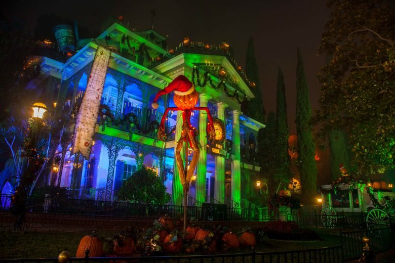 Atração Haunted Mansion Holiday iluminada com temática natalina e elementos de Halloween.